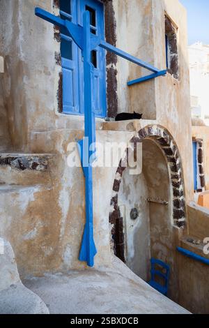Schwarze Katze vor einer blauen Eingangstür zu einem Haus in Oia, Santorin, Griechenland Stockfoto