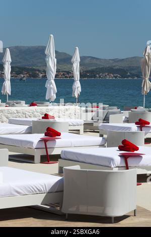 Weiße Liegestühle mit roten Handtüchern an der Küste mit Blick auf das Meer, Amadria Park, EN Vogue Beach Club, sibenik, sibenik, Dalmatien, Kroatien, Europa Stockfoto