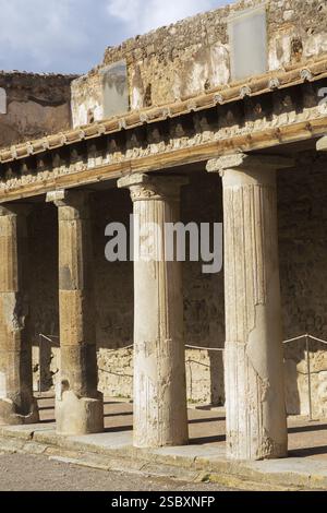 Altes großes Gebäude, das mit Terrakotta-Tonziegeln bedeckt und von Steinsäulen gestützt ist, an den antiken Ruinen von Pompeji, Region Kampanien, Italien, EUR Stockfoto