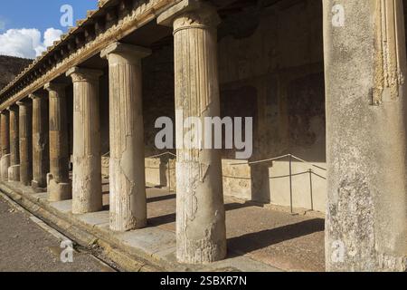Altes großes Gebäude, das mit Terrakotta-Tonziegeln bedeckt und von Steinsäulen gestützt ist, an den antiken Ruinen von Pompeji, Region Kampanien, Italien, EUR Stockfoto