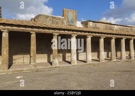 Altes großes Gebäude, das mit Terrakotta-Tonziegeln bedeckt und von Steinsäulen gestützt ist, an den antiken Ruinen von Pompeji, Region Kampanien, Italien, EUR Stockfoto
