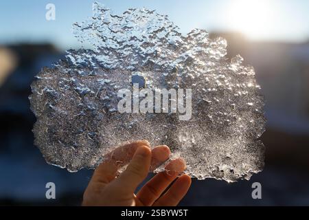 Meine Hand hält nachts ein Stück gefrorenes Wassereis bei eiskalten Temperaturen Stockfoto