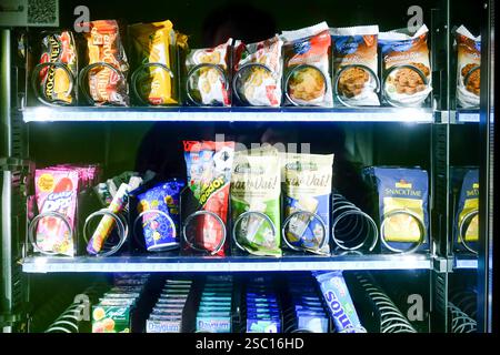 Cremona, Italien - 30. Januar 2025 das Bild zeigt einen gut beleuchteten Automaten mit verschiedenen verpackten Snacks. Die Auswahl umfasst Cookies, cra Stockfoto