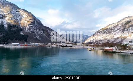 Aus der Vogelperspektive auf Gaupne, Norwegen, mit einem atemberaubenden Fjord, einem kleinen Hafen mit Booten und schneebedeckten Bergen rund um die malerische Stadt. Stockfoto