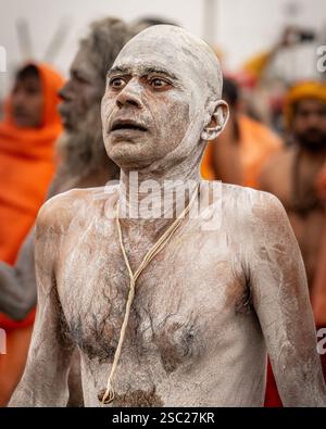 Ein neu hergestellter Naga Sadhu, durchnässt und mit Asche bedeckt, geht zurück zum Akhada, mit intensivem Blick und jenseits der Welt. Stockfoto