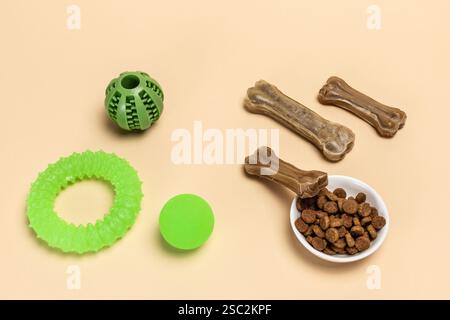 Trockenfutter und spielerisches Spielzeug für Hunde. Granuliertes Tierfutter in einer Schüssel und künstliches Hundekauen Knochenfutter mit Vitaminen. Bälle, ein Kaugummi-Kauknochen und Stockfoto
