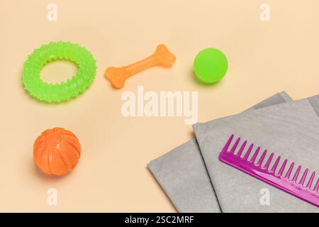 Haustierzubehör und verspielte Gegenstände, darunter ein Trainingspad, ein Kamm, Spielzeugkugeln, ein Gummiring und ein Kauknochen für Hunde. Stockfoto