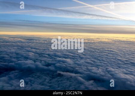 Wolkenmeer von oben gesehen durch das Bullauge des Flugzeugs bei Sonnenuntergang Stockfoto