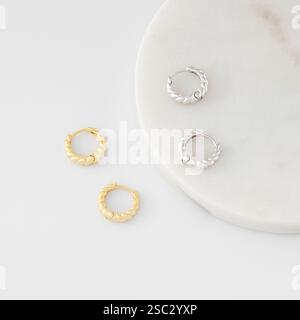 Stilvolle goldene und silberne Creolen sind auf weiß. Katalog von Schmuck Stockfoto