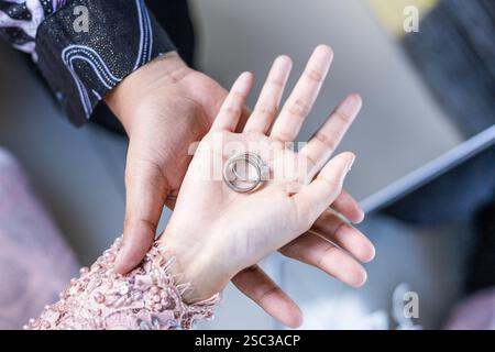 Der Bräutigam hält die Brauthände und die Ringe oben Stockfoto