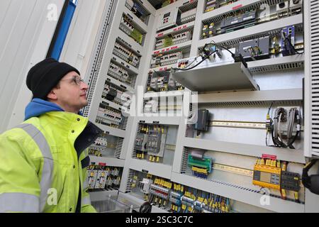 Wernigerode, Deutschland. Februar 2025. Bauleiter Malte Klebe öffnet den Schrank eines Batteriespeichersystems der EDF Renewables Deutschland GmbH. Das 2024 installierte Batteriespeichersystem wird in Zusammenarbeit mit der Hasseröder Brauerei GmbH betrieben. Quelle: Matthias Bein/dpa/Alamy Live News Stockfoto