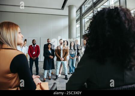Eine Gruppe von Geschäftsleuten, die an einem Seminar in einem modernen Arbeitsbereich teilnehmen und sich auf Zusammenarbeit und berufliche Entwicklung konzentrieren. Stockfoto