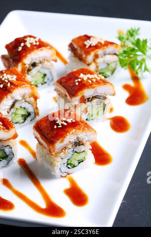 Unagi Maki Roll auf weißem Teller Hintergrund Sushi Roll mit gegrilltem Aal und Gurke, Spargel dick, Sesam mit spezieller Sauce Stockfoto