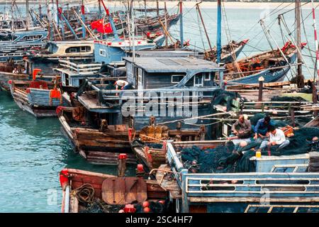 Fischerboote legten in einem chinesischen Hafen mit Fischern an, die Netze verwalten. Stockfoto