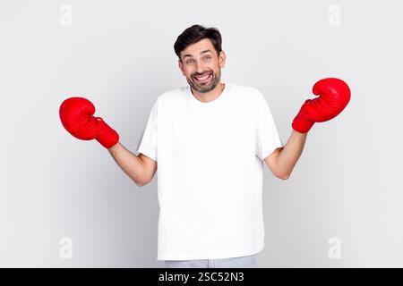 Ein lässiger, gutaussehender junger Mann mit Boxhandschuhen, der eine verspielte Geste vor grauem Hintergrund macht Stockfoto