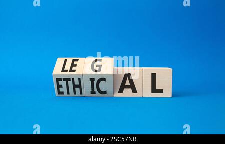 Ethisches und rechtliches Symbol. Gedrehte Holzwürfel mit den Worten ethisch und legal. Wunderschöner blauer Hintergrund. Geschäftliche und ethische und rechtliche Konzepte. Kopie sp Stockfoto