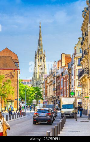 Lille, Frankreich, 4. Juli 2023: Straße mit Auto fahren, alte Farbbauten und römisch-katholische Kirche Eglise Saint-Maurice im historischen Zentrum, Französisch F Stockfoto