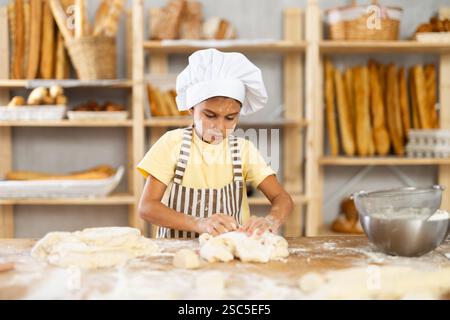 Mädchen, die in der Bäckerei arbeiten, als Bäckerin arbeiten, Teig kneten, mit Mehl arbeiten. Stockfoto
