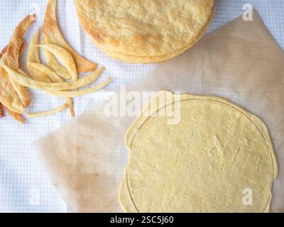 Kochen eines Napoleon-Kuchens mit einem Haufen gebackener dünner Butterschichten, einer rohen Schicht, die auf Backpapier und Teigresten ausgerollt wurde Stockfoto