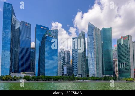 Die hoch aufragenden Bürogebäude des Marina Bay Financial Centre und Raffles Quay überblicken das grüne Wasser der Marina Bay in Singapur Stockfoto