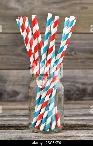 Papierhalme im Glas auf hölzernem Hintergrund Stockfoto