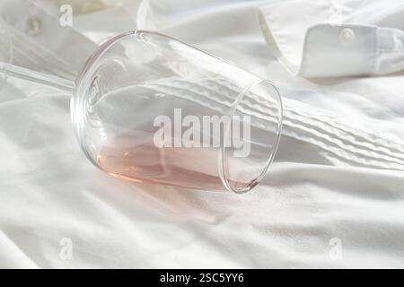 Glas, mit rosafarbenem Wein, verschüttet auf einem weißen Hemd, Nahaufnahme, selektiver Fokus, keine Leute, Konzept, Draufsicht Stockfoto