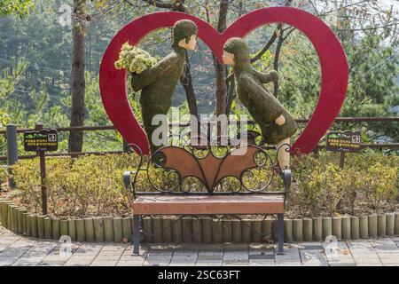 Cheongyang-Gun, Südkorea, 2. Oktober 2020: Nur für redaktionelle Zwecke. Statue eines Paares, das sich vor rotem Herzen im Waldpark in Asien küssen will Stockfoto