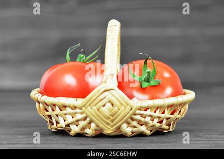 Frische Tomaten im Korb auf hölzernem Hintergrund Stockfoto