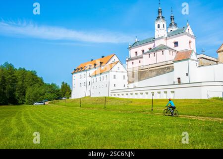 Radfahrer fahren mit dem Fahrrad entlang der Kirche im Klosterkomplex Camaldolese auf der Halbinsel Wigry See, Podlasie, Polen Stockfoto