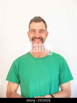 Porträt eines weißen Mannes mittleren Alters mit freundlichem Schnurrbart und grünem T-Shirt Stockfoto