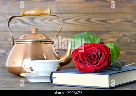 Alles Gute zum Muttertag: Rote Rose, Buch und Tasse Tee auf hölzernem Hintergrund Stockfoto