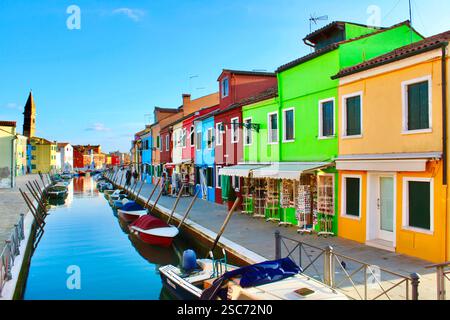 Farbenfrohe Häuser, die sich auf dem Kanal in Burano spiegeln. Ein berühmtes Touristenziel, bekannt für seine pulsierende Architektur. Burano, Venedig, Italien – Januar 2023. Stockfoto