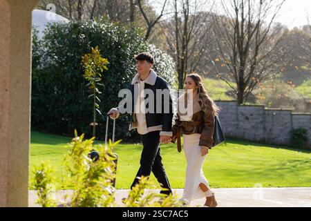 Junge Paare gehen Hand in Hand, kommen in einem wunderschönen Hotel oder Resort mit einem rollenden Koffer an und genießen einen entspannenden Urlaub voller J Stockfoto