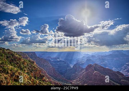 Sonnenstrahlen, die durch Wolken über dem Grand Canyon brechen und zerklüftete Klippen und weite Landschaften unter einem dramatischen Himmel hervorheben. Stockfoto