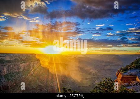 Sonnenuntergang über dem Grand Canyon bei Sonnenuntergang, goldenes Licht durch nebelige Luft mit dramatischen Klippen und einem lebendigen Himmel. Stockfoto