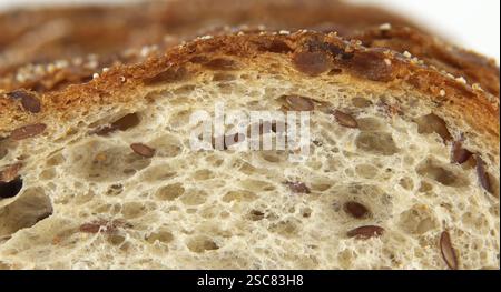 Nahaufnahme mit einer Scheibe Mehrkornbrot, die Textur, Samen und Kruste hervorhebt. Ideal für Themen wie Backen, gesunde Ernährung und Kunst Stockfoto