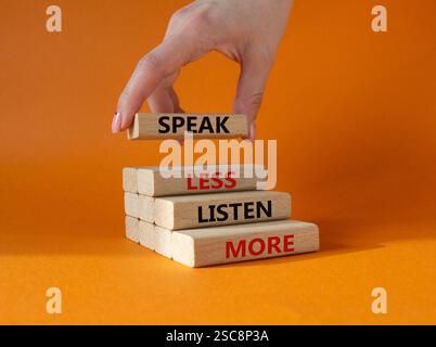 Weniger sagen, mehr hören. Holzblöcke mit Wörtern sprechen weniger Hören Sie mehr. Wunderschöner orangefarbener Hintergrund. Geschäftsmann Hand. Geschäftlich und weniger sprechen Stockfoto