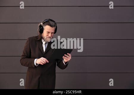 Eleganter reifer Mann mit Tablet und Kopfhörern Stockfoto