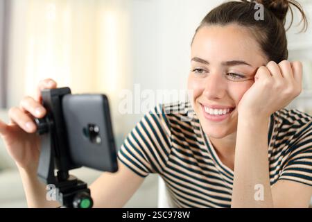 Glücklicher Influencer, der das Smartphone für die Aufnahme von Videos zu Hause vorbereitet Stockfoto