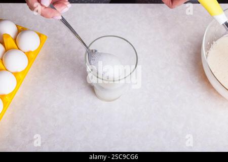 Cupcakes zu Hause machen. Eine Frau bereitet in der Küche Osterkuchen zu, indem sie Limonade in ein Glas schlägt. Stockfoto