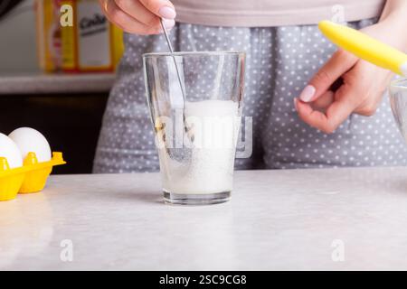Cupcakes zu Hause machen. Eine Frau bereitet in der Küche Osterkuchen zu, indem sie Limonade in ein Glas schlägt. Stockfoto