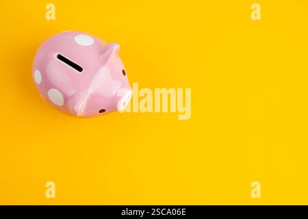 Finanzielle Einsparungen. Pinkfarbene Piggy Bank auf gelbem Hintergrund, flache Lage mit Platz für Text. Stockfoto