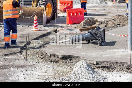 Bauarbeiter, die Straßen aktiv reparieren und schwere Maschinen in städtischen Gebieten einsetzen Stockfoto