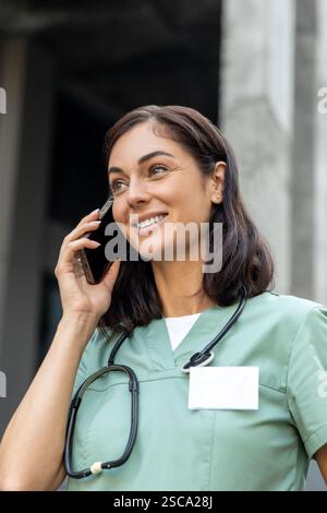 Junge Ärztin, die mit einem Patienten telefoniert und engagiert und freundlich aussieht Stockfoto