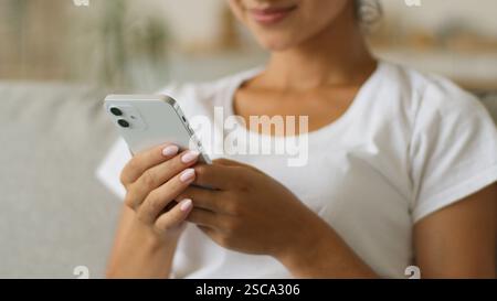 Glückliche lächelnde indische Frau mit Smartphone zu Hause positives Lachen Arabische Mädchen Frau hält Handy scrollend Social Media Online Shopping Stockfoto