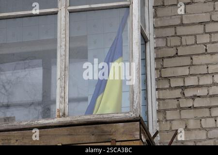 DNIPRO, UKRAINE - 5. FEBRUAR 2025 - die Nationalflagge der Ukraine wird auf dem Balkon eines mittelhohen Gebäudes gesehen, das durch russischen Beschuss beschädigt wurde, Dnipro, Ostukraine (Foto: Mykola Miakshykow/Ukrinform) Stockfoto