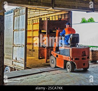 Gabelstaplerfahrer im Overall bei der Arbeit im Lager Stockfoto