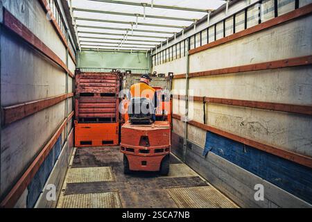 Gabelstaplerfahrer im Overall bei der Arbeit im Lager Stockfoto
