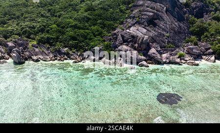 Unberührte tropische Küste mit kristallklarem Flachwasser und felsigem Ufer. La Digue, Seychellen. Stockfoto