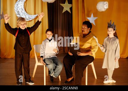 Gruppe von Kindern und Lehrern, die an pädagogischen Spielaktivitäten in Innenräumen teilnehmen, mit Sternen und Monddekorationen im Hintergrund, die eine fantasievolle Umgebung schaffen Stockfoto